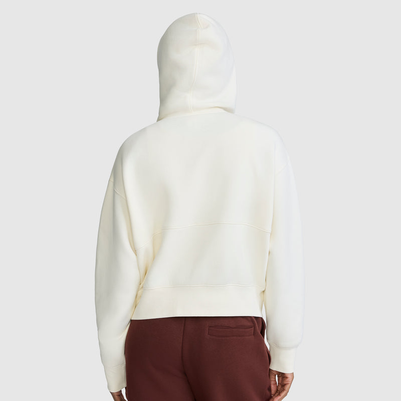 A person is shown from the back against a plain light gray background, wearing a Champion Training Half-Zip Fleece Hoodie with the hood up and maroon pants.