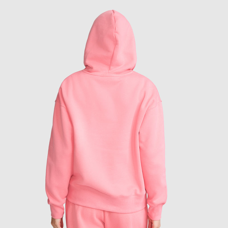 A person wearing the Champion Fleece Hoodie with Satin Applique in pink, along with matching pink pants, stands with their back to the camera against a plain light gray background.