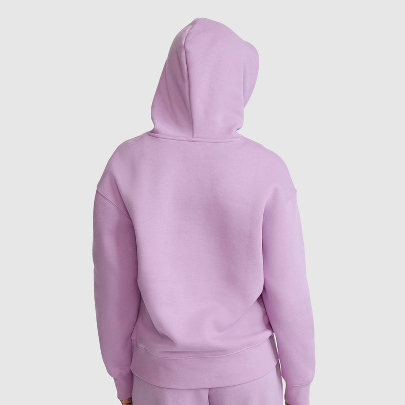 A person is shown from the back, standing against a plain white background, wearing a light purple Champion Fleece Hoodie, Satin Applique, and matching pants.