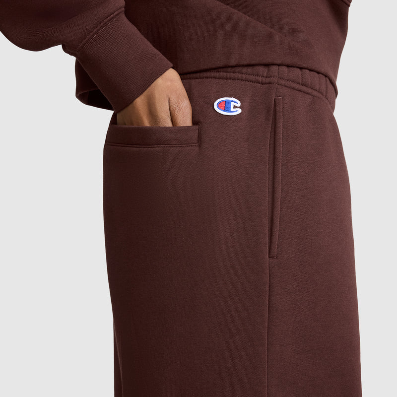 A person wearing brown Champion Fleece Cargo Training Pants and a matching sweatshirt has their hand in their pocket. The Champion logo is visible near the waistband, emphasizing the cozy style of the Fleece Cargo Training Pant by Champion.