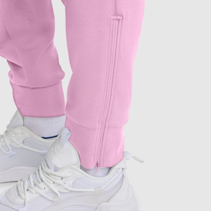 Close-up of a person wearing the Champion Taper Leg Jogger with Zippers in light pink, paired with white socks and white athletic sneakers, set against a plain light gray background.