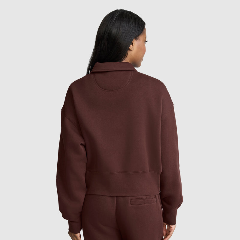 A woman stands facing away against a plain light gray background, wearing the Champion Fleece Training Polo in a matching maroon set.