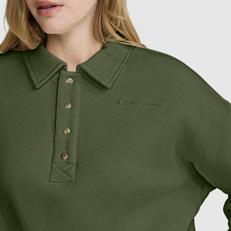A person is seen wearing the Champion Fleece Training Polo in olive green, featuring a collared neckline and button details. The image highlights only the lower face and upper torso, emphasizing the stylish and comfortable fleece pullover design for women.