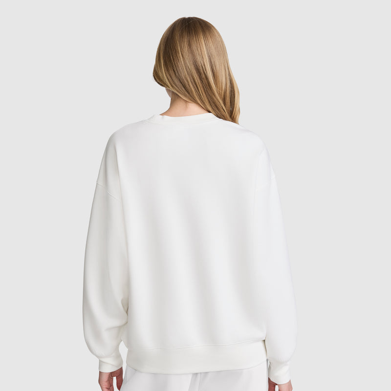A person with long, light brown hair is seen from behind, wearing the Champion Crewneck Pullover Sweatshirt that creates an athletic silhouette, paired with matching white pants against a plain light gray background.