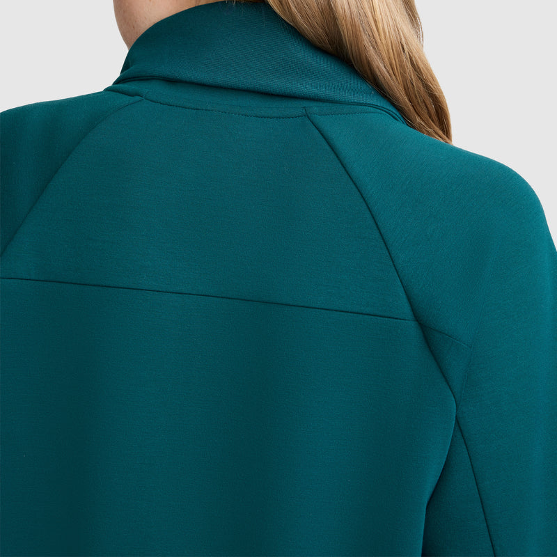 Close-up of a person’s upper back and shoulder, wearing a teal Champion Quarter-Zip Pullover with a high collar. The person has long light brown hair, and the background is plain light gray.