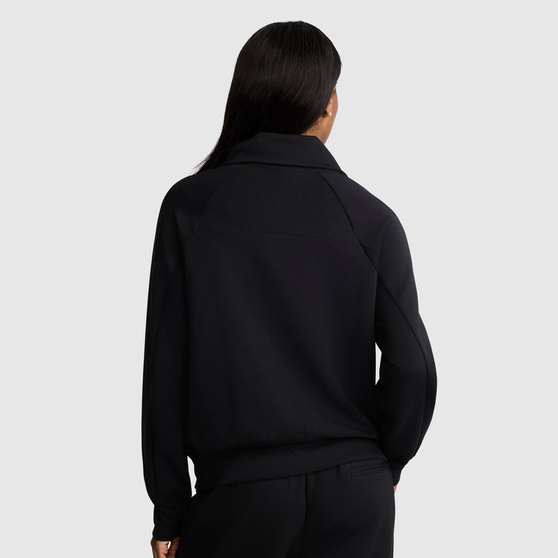 A person with long, dark hair is shown from the back, wearing a black Champion Quarter-Zip Pullover and matching black pants against a plain light gray background.