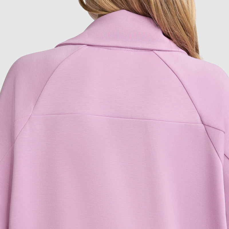 The back view of a person wearing the Champion Quarter-Zip Pullover in light pink, featuring a collared design, with long light brown hair visible against a plain light grey background.