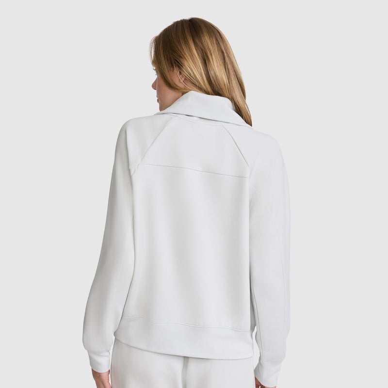 A person with long, light brown hair is shown from the back, wearing the Champion Quarter-Zip Pullover in white along with matching white pants against a plain light background.