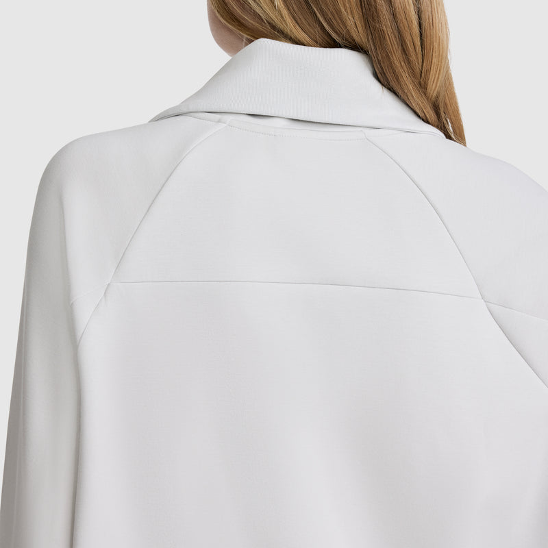 The back view shows a person wearing the Champion Quarter-Zip Pullover in white. Their light brown hair falls over their shoulder, while the pullover’s stitching details stand out, accentuating its stretch poly-modal fabric.