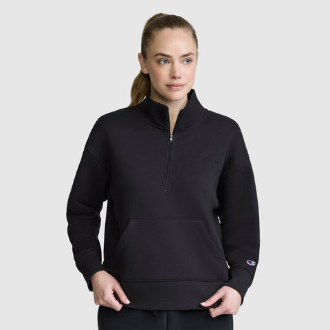 A woman wearing a black Champion Fleece Mockneck Quarter-Zip stands facing forward against a plain light gray background, showcasing effortless sport style.