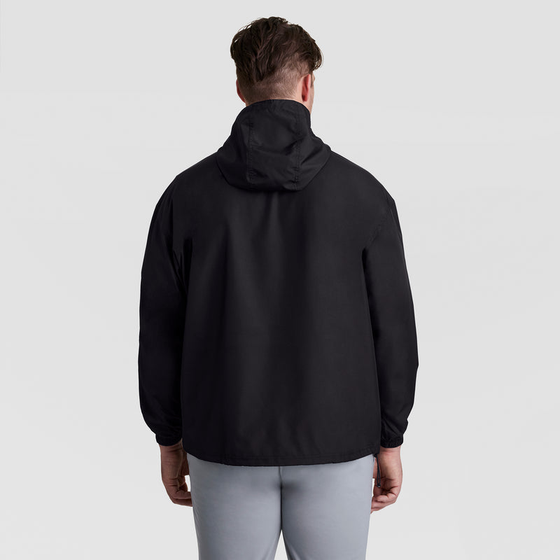 A person faces away from the camera wearing the Champion Stadium Packable Jacket, Script Logo - Big & Tall in black and light gray pants, standing against a plain light gray background.