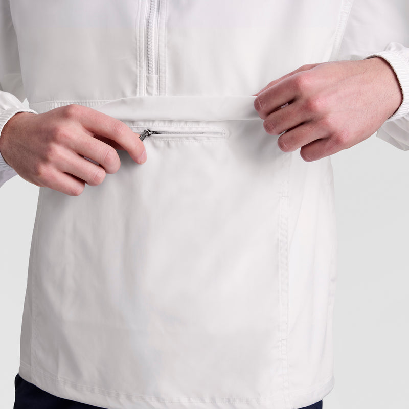 A person wearing the Champion Stadium Packable Jacket with Script Logo is unzipping a small front pocket, focusing on the zipper and pocket area; only their hands and torso are visible.