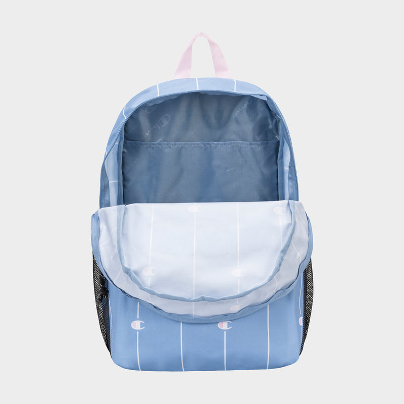 The Champion Kids' Merit Backpack is light blue with white vertical stripes, a pale pink top handle, and black mesh side pockets. It features a durable polyester build, an open main compartment, and a subtle repeating logo pattern.