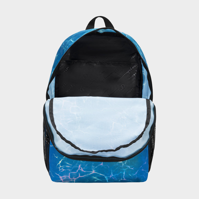The Champion Kids' Merit Backpack features a blue water ripple design, black zippers, sturdy handle, and black mesh side pockets. Made of durable polyester, it's shown open with unzipped main compartment and front pocket.