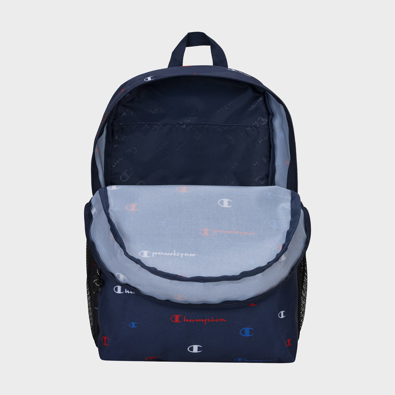 A durable navy blue Champion Kids' Merit Backpack with a front pocket unzipped, showing the inside. It features a repeating white, red, and blue Champion logo pattern on the exterior and interior lining.