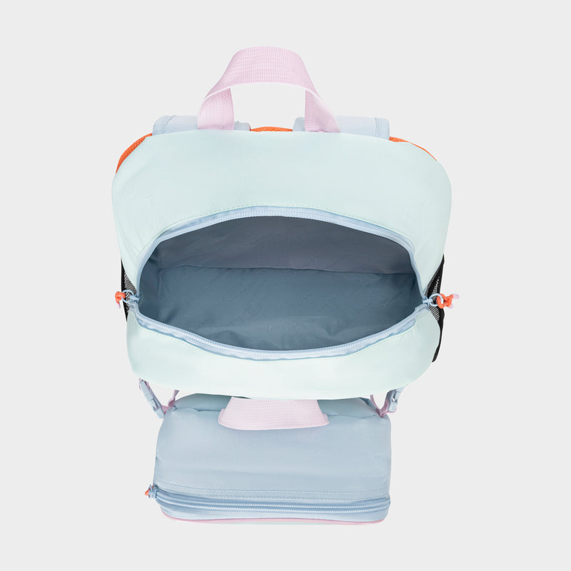 The Champion Kids' Mode Lunch Kit & Backpack Combo features a pastel design with pink handles and zipper pulls. Its open main compartment and partially open bottom reveal a roomy, light blue interior.
