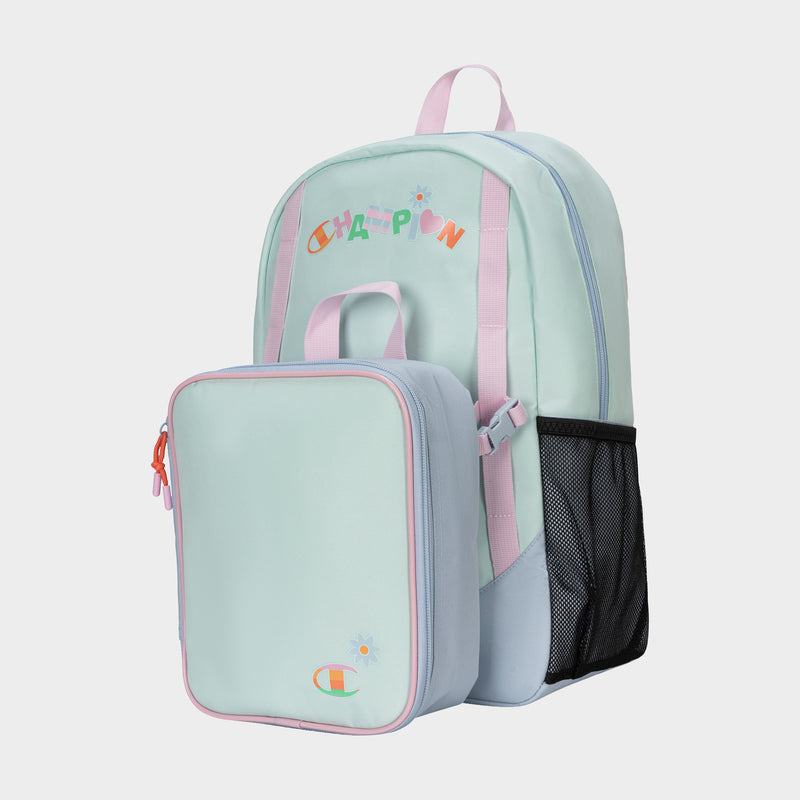 The Champion Kids' Mode Lunch Kit & Backpack Combo features a pastel mint green and light blue backpack with pink accents, black mesh side pocket, and matching insulated lunch box. "CHAMPION" is playfully printed in colorful letters on the backpack.