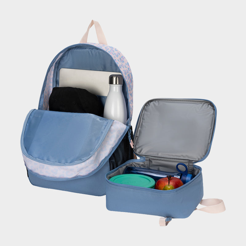 The Champion Kids' Mode Lunch Kit & Backpack Combo in blue features an open front pocket showing a laptop, black cap, and white water bottle. Nearby, the insulated lunch kit holds apples, a green food container, and blue scissors—perfect for every day.