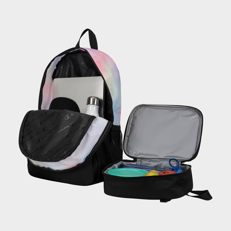 A pastel tie-dye Champion Kids' Mode Lunch Kit & Backpack Combo sits open, revealing a laptop and white water bottle in the backpack, while the insulated polyester lunch box beside it holds food containers and utensils.