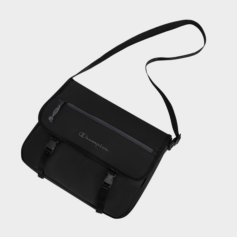 The Champion Phase Messenger Bag features a black design with a long adjustable shoulder strap, front zippered pocket, padded laptop sleeve, dual buckle closures, and an embroidered Champion logo on the flap.