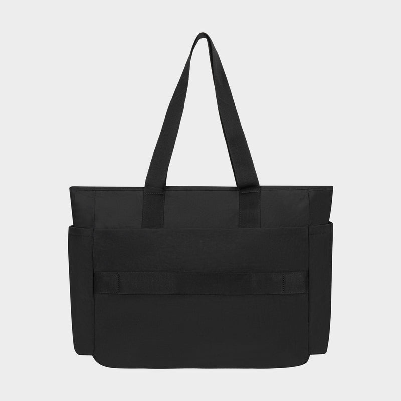 The Champion Quartz East West Tote is a lightweight crinkle nylon bag with two long shoulder straps, side pockets, a large front pocket, and a padded laptop sleeve, shown against a plain light gray background.
