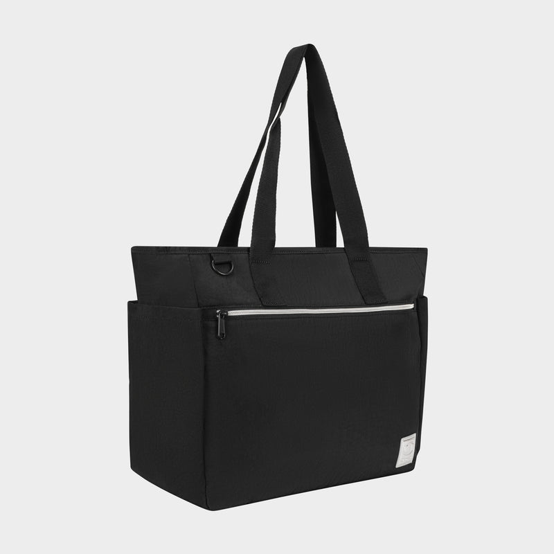 The Champion Quartz East West Tote is a black lightweight crinkle nylon bag with long shoulder straps, front zipper and side pockets, a small white label, and padded laptop sleeve—ideal for travel. Shown against a plain light background.
