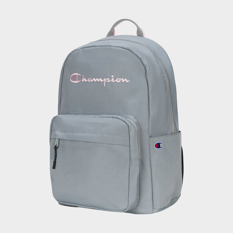 The Champion Steady Backpack in light gray features a front zipper pocket, side pocket, top handle, and the Champion logo embroidered in pink and white on the front.