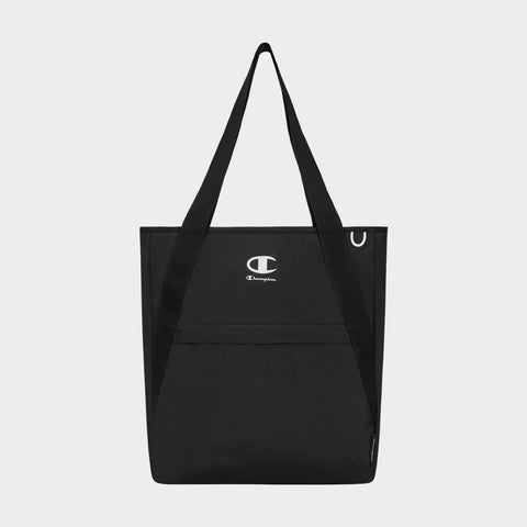 A Champion Lottie Tote in black, featuring dual handles, a front pocket, and a centrally placed white Champion logo. Made from sturdy nylon, this versatile everyday bag is showcased against a plain light gray background.