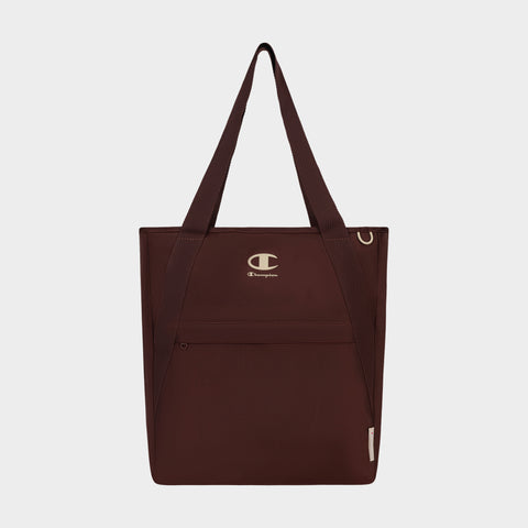 The Champion Lottie Tote, presented in maroon and made from sturdy nylon, features dual straps, a convenient front zip pocket, and prominently displays the iconic Champion logo on the upper front. Photographed on a plain white background, this versatile everyday bag blends style with durability.