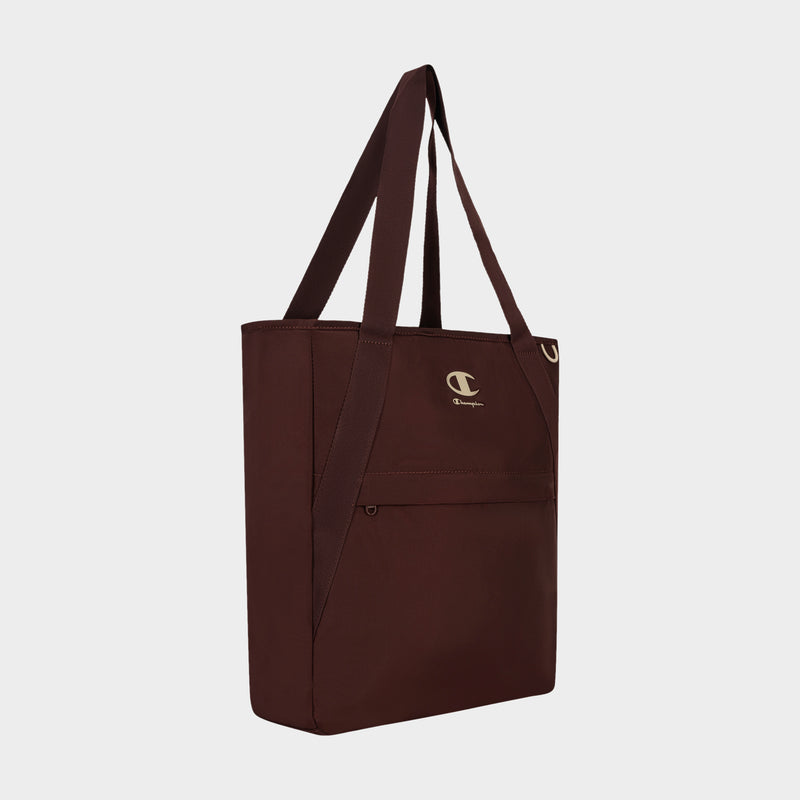 Introducing the Lottie Tote by Champion: a maroon nylon tote bag designed for durability, featuring long handles, a front zip pocket, and a small white Champion logo above the pocket. This versatile everyday accessory is showcased against a plain white background.