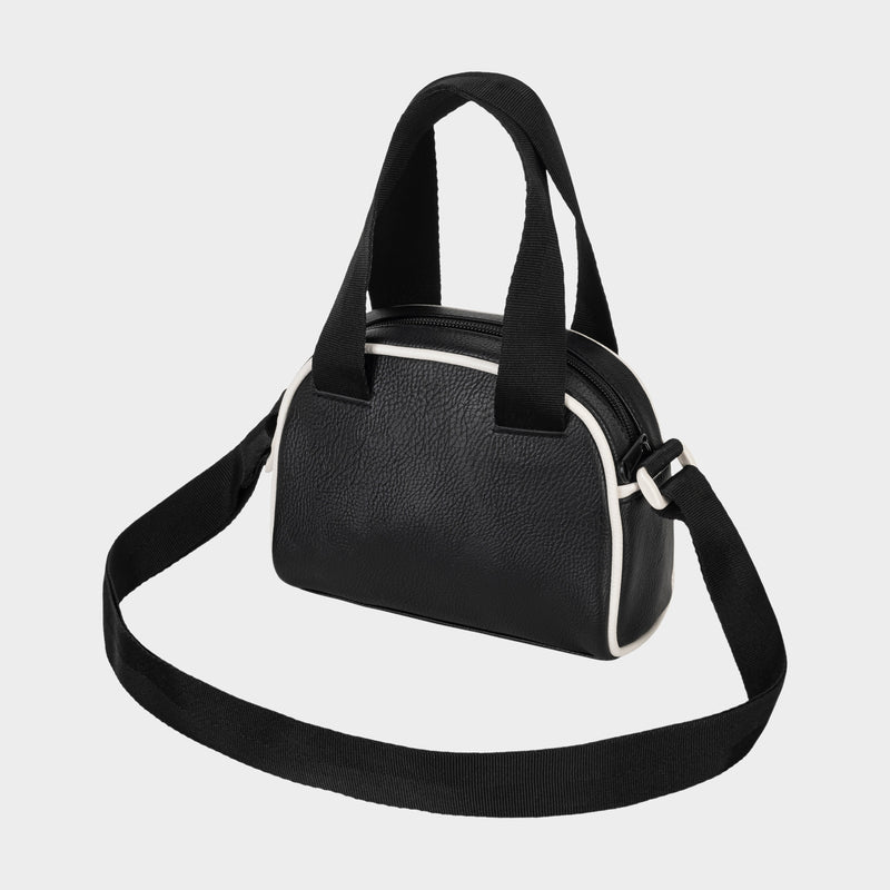 The Champion Hudson Mini Bowler Bag is a small, black bag with white trim, featuring two short handles, an adjustable strap for versatile carrying options, and an interior zip pocket—all displayed against a plain light gray background.