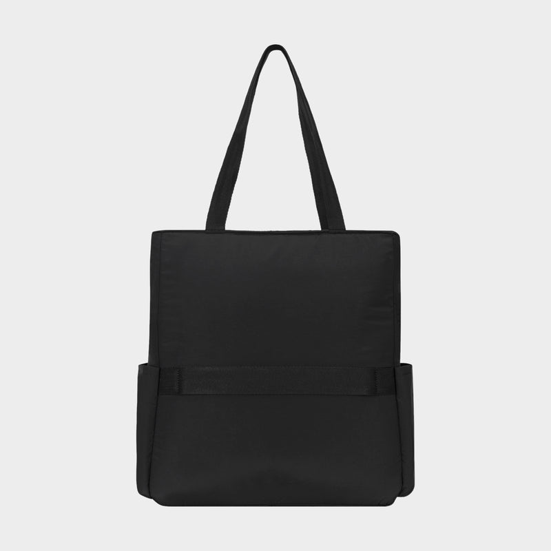 The Champion Explore Tote is a durable crinkle nylon tote bag in plain black, featuring two handles, two side pockets, and a simple rectangular silhouette, displayed against a light gray background.