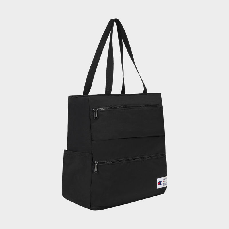 The Champion Explore Tote is crafted from durable black crinkle nylon and features two zippered front pockets, double shoulder straps, a convenient side pocket, an interior padded laptop sleeve for added protection, and a small Champion logo patch near the bottom right corner.