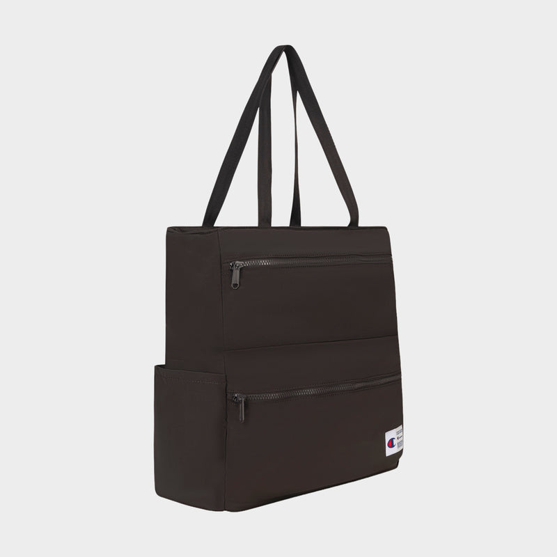 Introducing the Champion Explore Tote—a black crinkle nylon tote bag designed with two zippered front pockets, a side pocket, and long handles for comfortable carrying. This stylish tote features a padded laptop sleeve for extra convenience and protection, along with a lower front pocket adorned by a small Champion logo patch. Displayed against a white background.