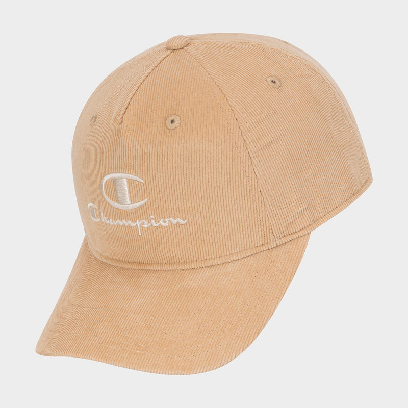 The Pursuit Corduroy Adjustable Cap by Champion is shown in tan corduroy with a white embroidered “C” and Champion logo on the front, displayed at an angle against a plain white background. It features a classic snapback closure for an adjustable fit.