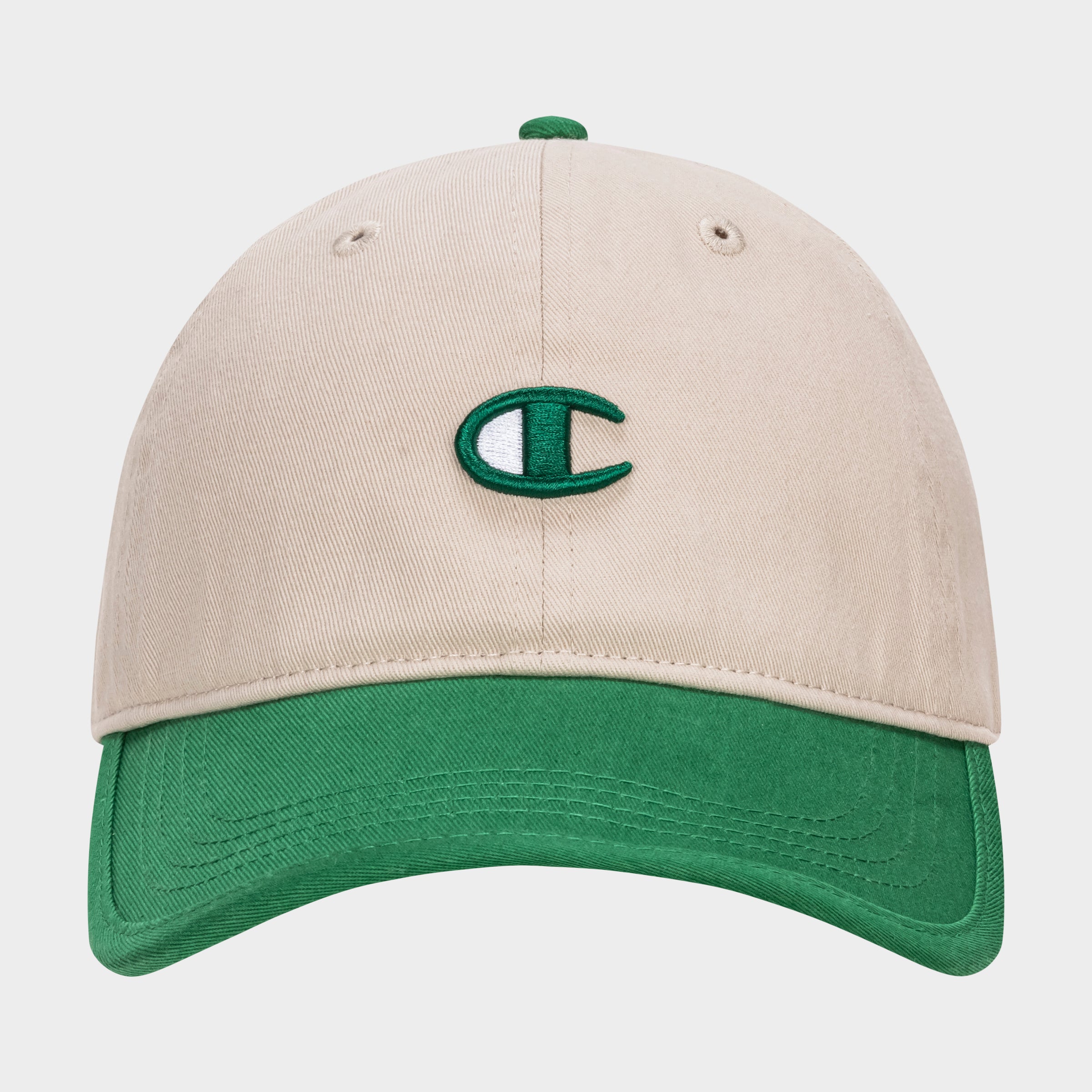 The Champion Briggs Washed Cotton Twill Adjustable Baseball Cap features a beige design with a green brim and a green and white embroidered C logo, crafted from washed cotton twill and shown on a plain white background.