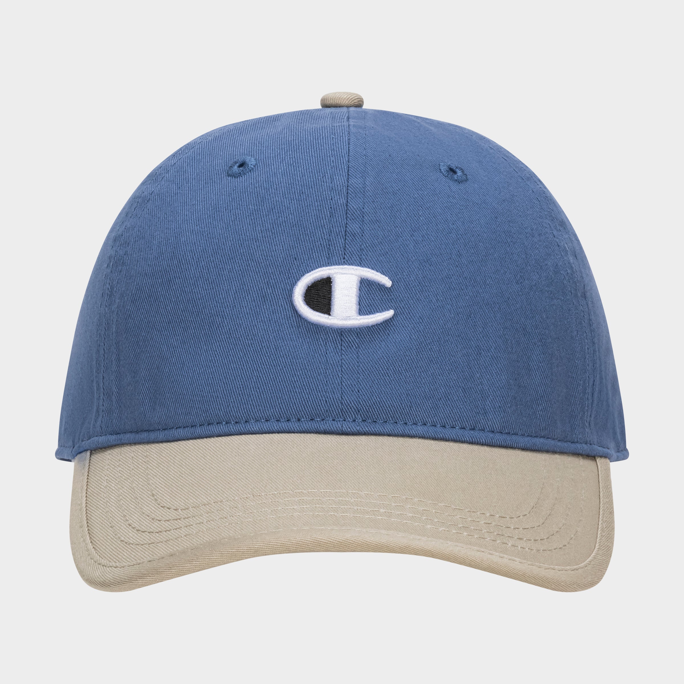 The Champion Briggs Washed Cotton Twill Adjustable Baseball Cap in blue features a beige brim and an embroidered white C logo on the front, displayed against a plain white background.