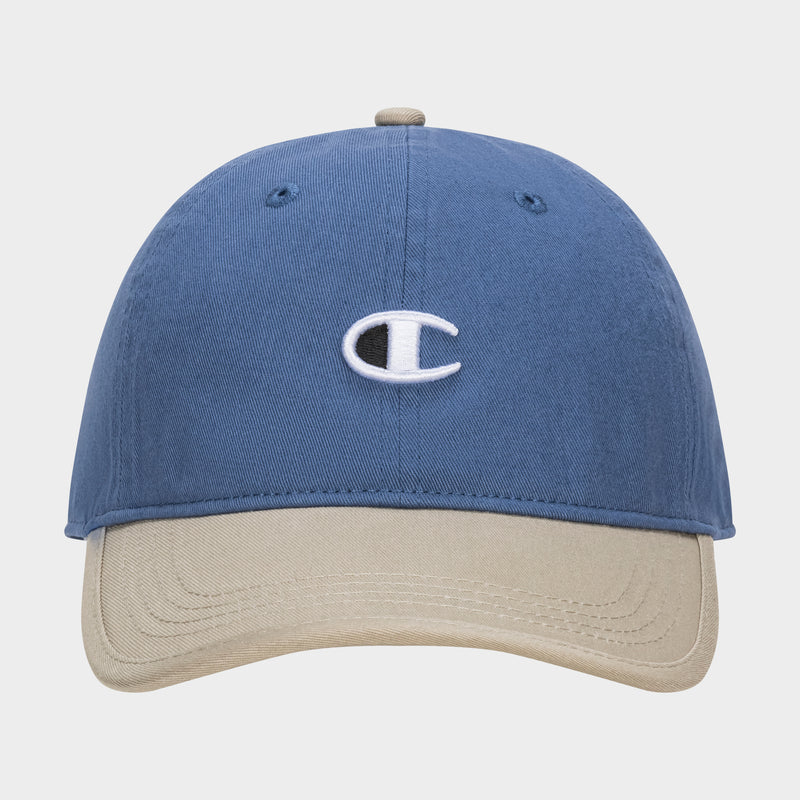 The Champion Briggs Washed Cotton Twill Adjustable Baseball Cap in blue features a beige brim and an embroidered white C logo on the front, displayed against a plain white background.
