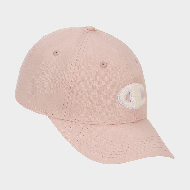 The Amber Chenille Adjustable Cap by Champion is a light pink cap with a relaxed fit, featuring a curved brim and an embroidered white chenille C logo patch on the front left side, displayed against a plain white background.