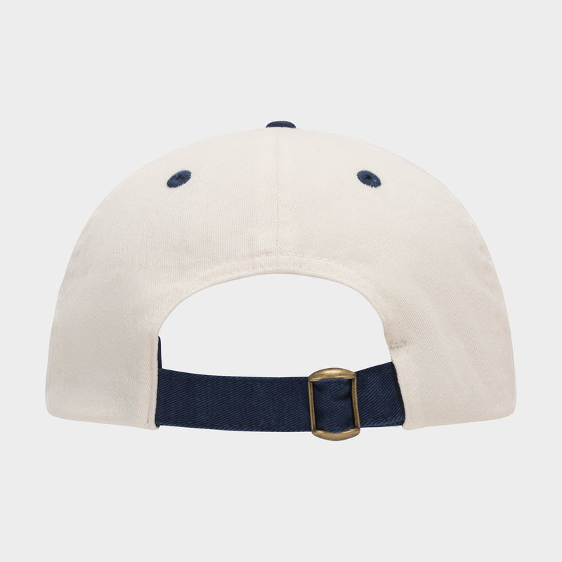 The Champion Amor Adjustable Baseball Cap in white cotton twill is shown from the back, with a navy blue adjustable strap, brass buckle, and two navy stitched eyelets.