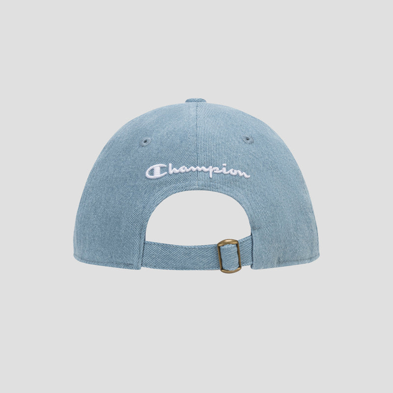 The Glen Denim Adjustable Baseball Cap by Champion is shown from the back in light blue denim, featuring a white Champion logo and an adjustable strap with a brass buckle. The plain, light-colored background highlights the classic style of this iconic hat.