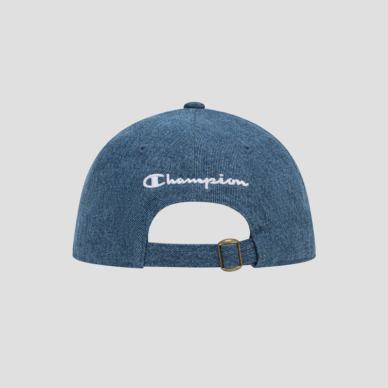 The Glen Denim Adjustable Baseball Cap by Champion is shown from the back in blue denim, featuring white embroidered Champion lettering and an adjustable strap with a brass buckle.