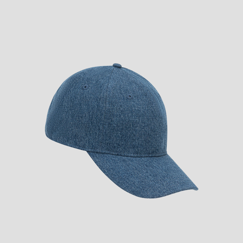 The Glen Denim Adjustable Baseball Cap by Champion is a plain blue denim baseball cap with a curved brim and an adjustable design for the perfect fit, displayed on a light gray background.