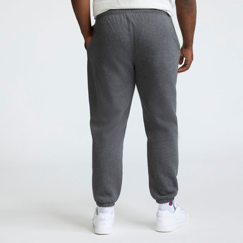 A person in a white T-shirt, Champion Powerblend Sweatpants with Cinched Bottom and C Logo (Big & Tall), and white sneakers stands with their back to the camera against a plain light background.