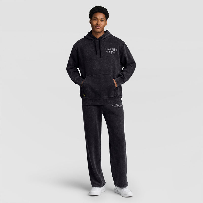 A man wears a black mineral wash Mineral Wash Pullover Hoodie, C Patch Logo with matching sweatpants and white sneakers.