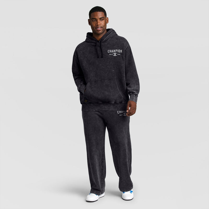 A man wearing a charcoal grey Mineral Wash Pullover Hoodie, C Patch Logo and matching sweatpants, both featuring white logo text.