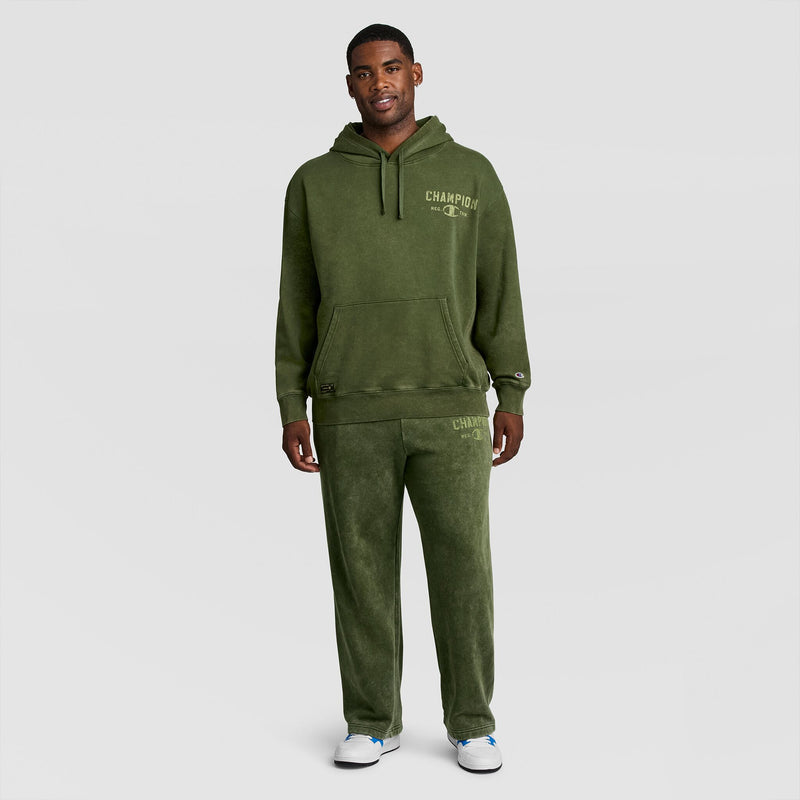 A man wearing a mineral wash Mineral Wash Pullover Hoodie, C Patch Logo and matching sweatpants, both featuring logo text on the chest and thigh.
