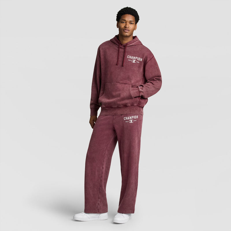 A person wearing a maroon mineral-wash hooded sweatshirt and matching Champion Mineral Wash Open Hem Pant, paired with white sneakers.