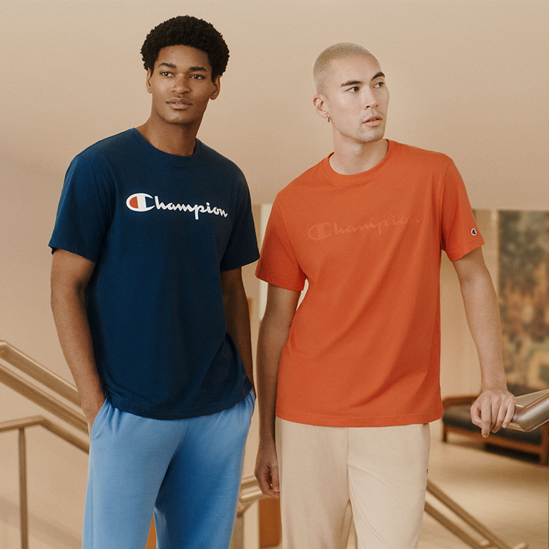 two men wearing script logo champion t-shirts in navy blue and orange 