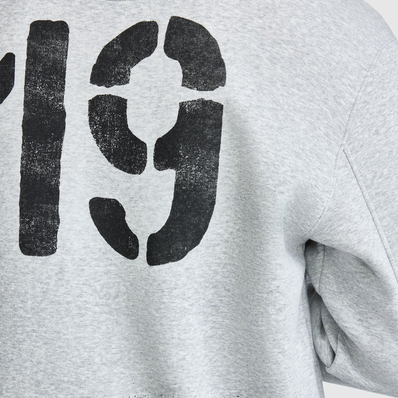 Close-up of a light gray Champion Fleece Baseball Jacket featuring the number 19 printed in large, distressed black stencil lettering.